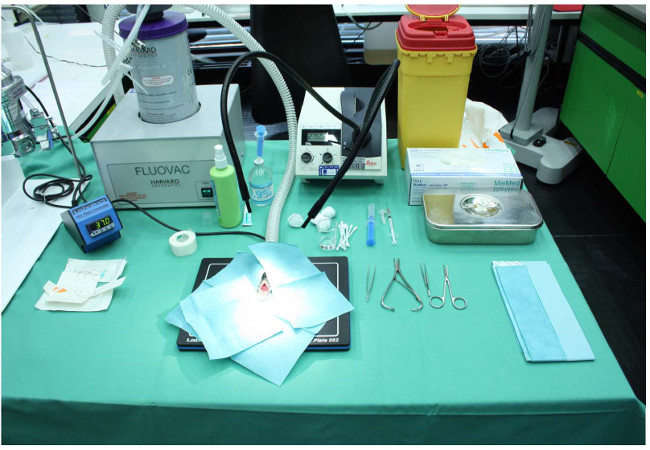 Surgical tools and sterilization equipment setup on a table for medical procedures.
