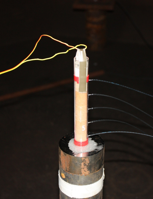 Static equilibrium diagram with wires on a vertical tube, illustrating balance in mechanics.