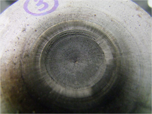 Polished metal surface under microscope, showing circular abrasion patterns; metallography study.