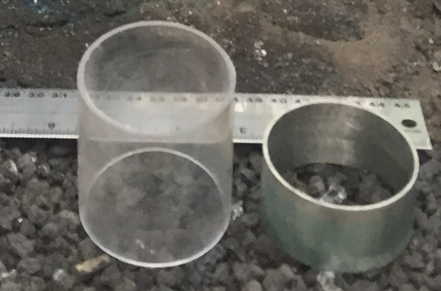 Transparent cylinder, metal ring on lab surface with ruler; geometry measurement experiment.