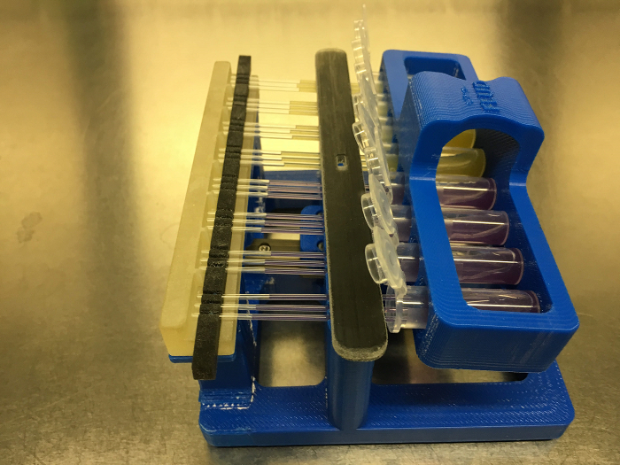 Lab chromatography setup with pipette tips for DNA separation in a blue 3D-printed rack.