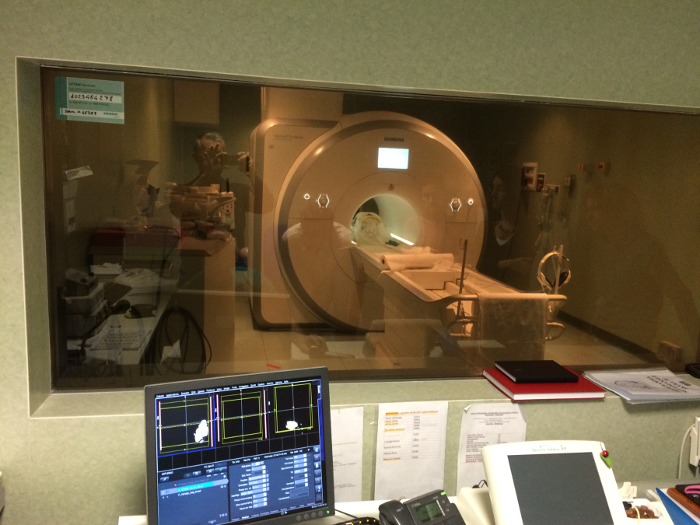 MRI scanner operation, control room view, medical imaging process, equipment setup, diagnostic analysis.