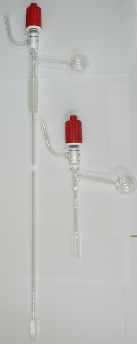 Glass chromatography columns with red caps, used for protein purification in laboratory setups.