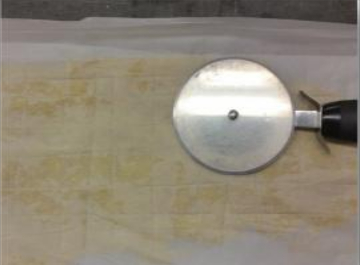 figure-protocol-5 Pastry dough scoring with pizza cutter tool on parchment paper.