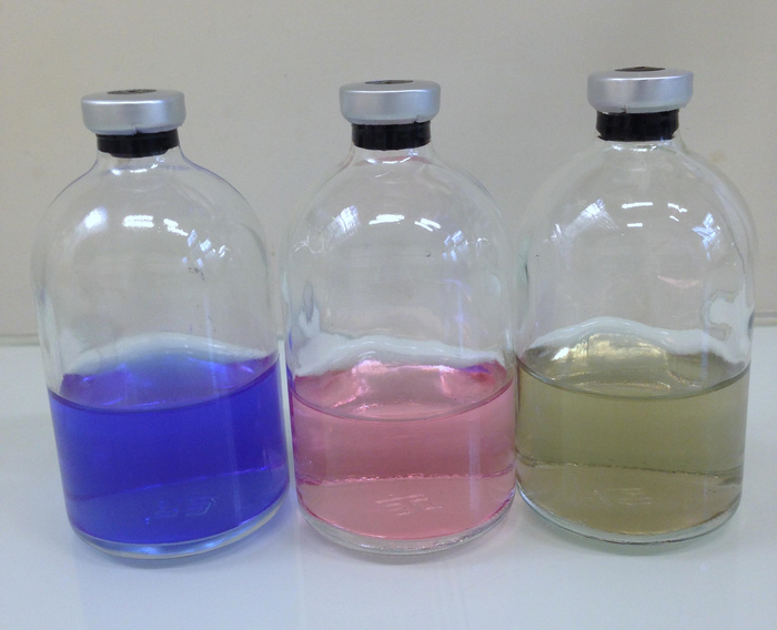 Chemical titration setup with color indicators in flasks; acid-base reaction experiment.