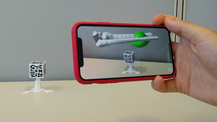 figure-results-6 Augmented reality app displaying bone structure on phone, using marker-based AR technology.