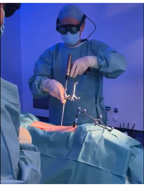 Surgical procedure, minimally invasive technique, doctor using specialized tools, operating room setup.