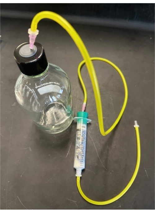 Vacuum filtration setup with tubing and syringe for liquid extraction in laboratory experiment.