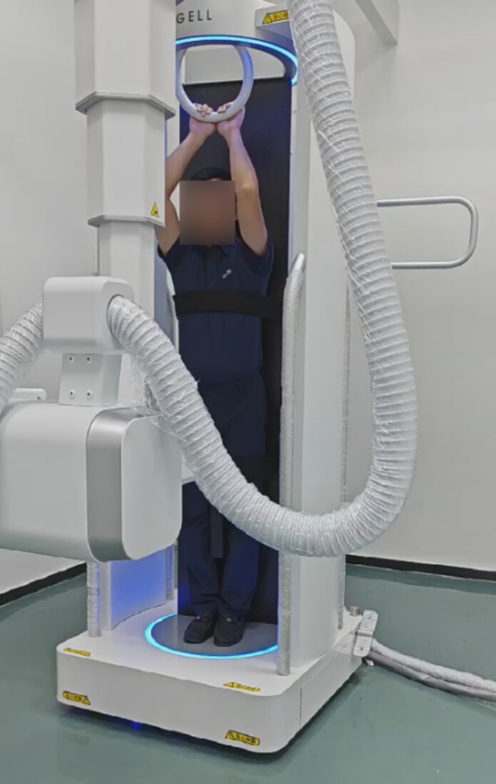 figure-results-4 Vertical CT scanner setup for whole-body imaging; person stands inside machine for scanning procedure.