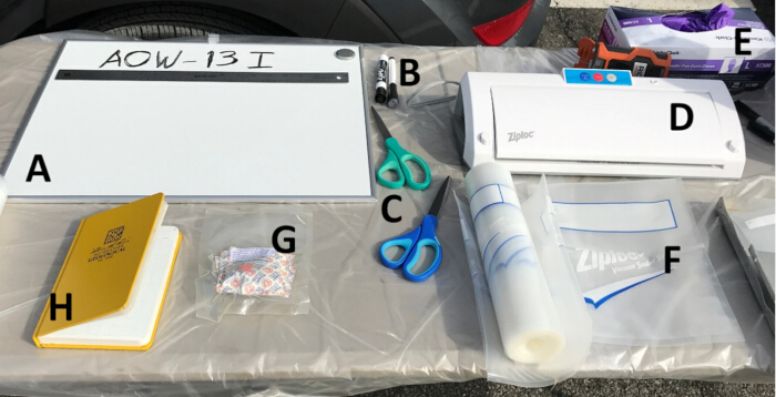Evidence preservation setup with labeling board, marker, scissors, and vacuum sealer for lab analysis.