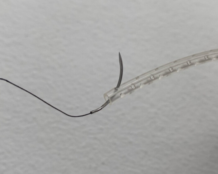 figure-results-3 Surgical needle with suture thread and clear tubing indicating medical suturing technique.