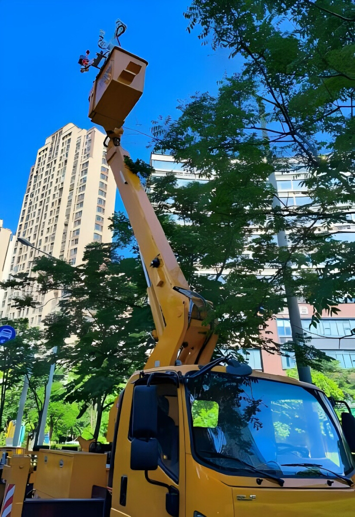 Aerial work platform lifting worker for maintenance on urban street with surrounding buildings.