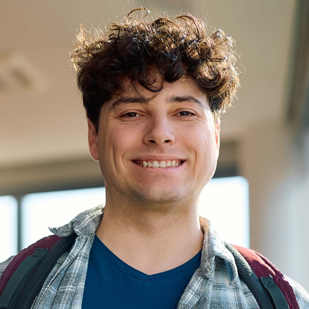 Smiling male student with a backpack in a classroom