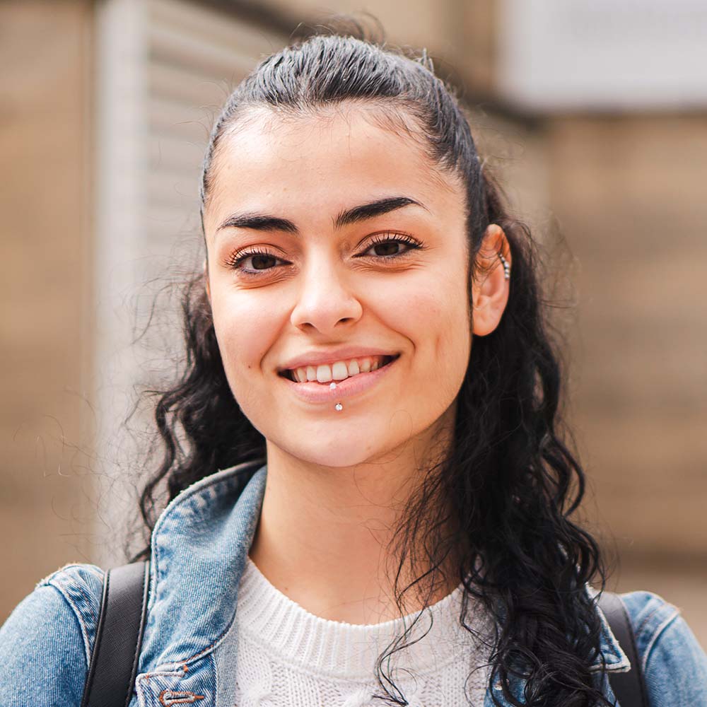 Smiling female student wearing a denim jacket outdoors
